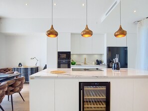 Ett modernt kök med vita skåp, en inbyggd ugn och ett kylskåp.