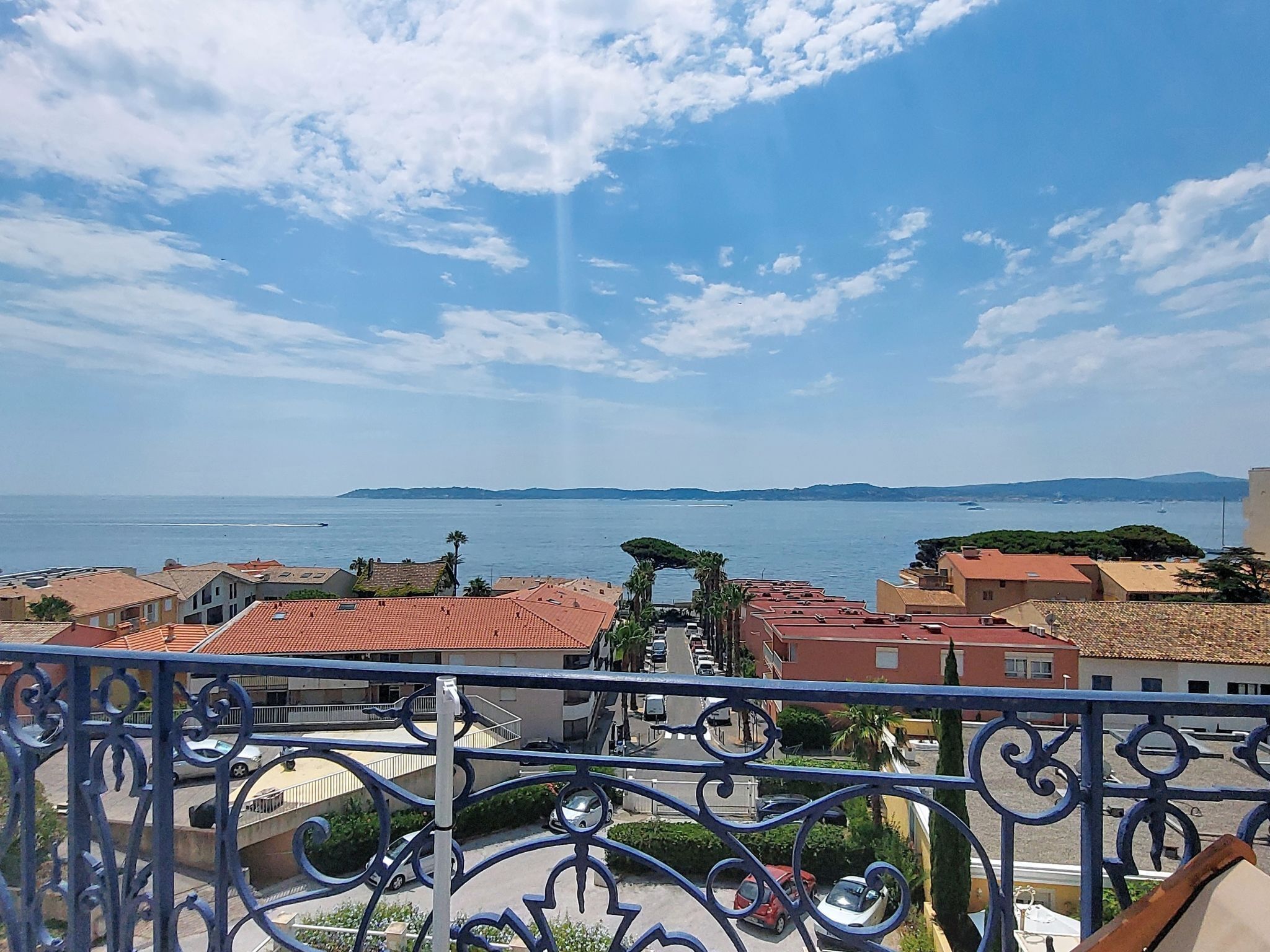 A balcony with a view of the sea, buildings, and a clear sky.
