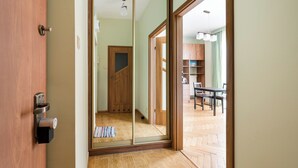 Una stanza con una porta in legno, una porta scorrevole in vetro, pavimento piastrellato, un armadietto in legno e una sedia.