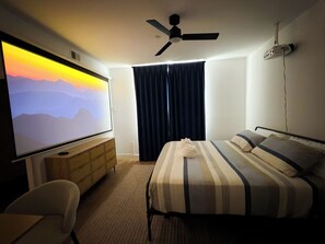 Ein Hotelzimmer mit Bett, Fernseher, Deckenventilator und einem Fenster mit Vorhängen.