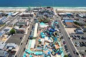 Vista aérea de un parque de atracciones costero con parque acuático, estacionamientos y una playa al fondo.