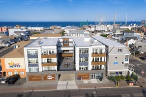 Ein modernes Hotel mit mehreren Etagen, einer überdachten Außenbereich-Sitzgelegenheit und Blick aufs Meer.