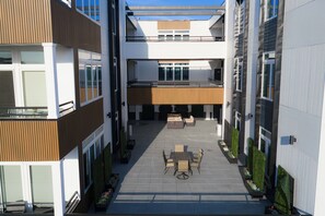 Un edificio moderno con un patio que cuenta con asientos al aire libre, una escalera y vistas al cielo.