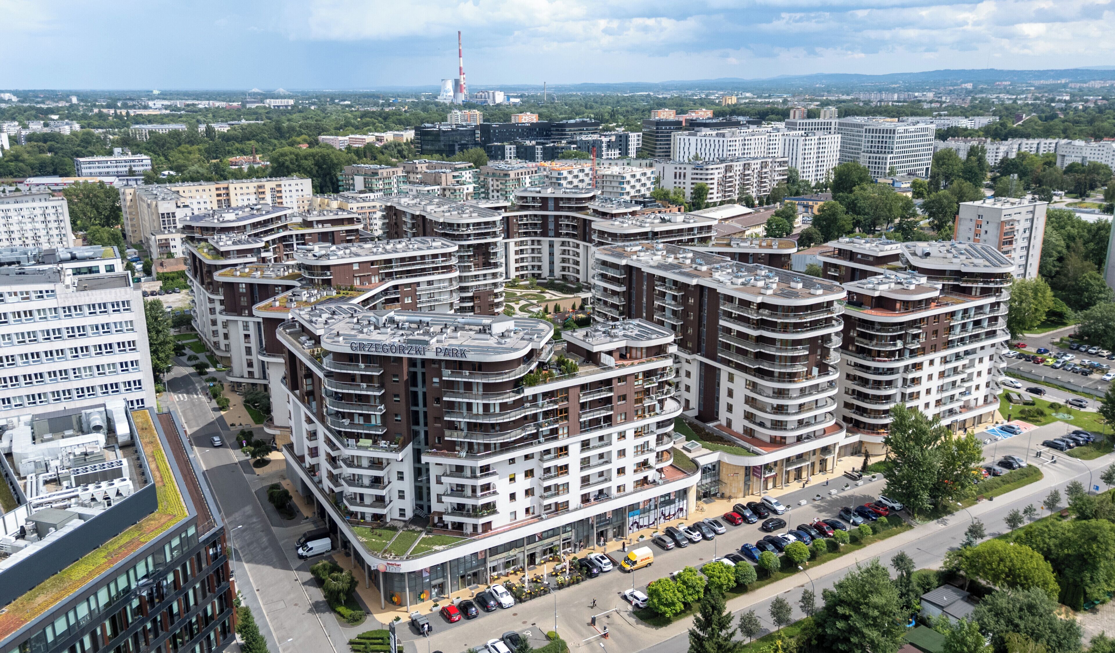 Un complex residencial modern amb diversos edificis alts, un pati central i una zona d'aparcament.