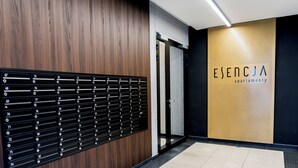 A hotel reception area with a wooden panel wall, a black mailbox system, and a sign for 'ESENCJA apartmenty'. - Warta River Esencja Apartment (Poznań)