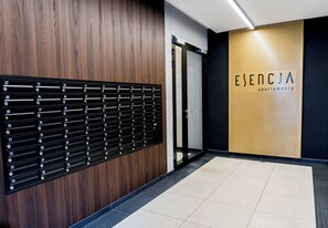 Ein Hotel-Empfangsbereich mit einer Wandpaneelausstattung aus Holz, einem schwarzen Briefkasten-System und einem Schild für 'ESENCJA apartmenty'.