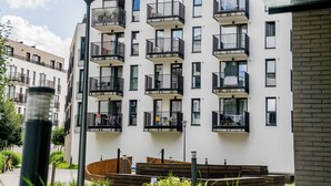 A multi-story residential building with balconies, a street lamp, and a small garden area. - Warta River Esencja Apartment (Poznań)