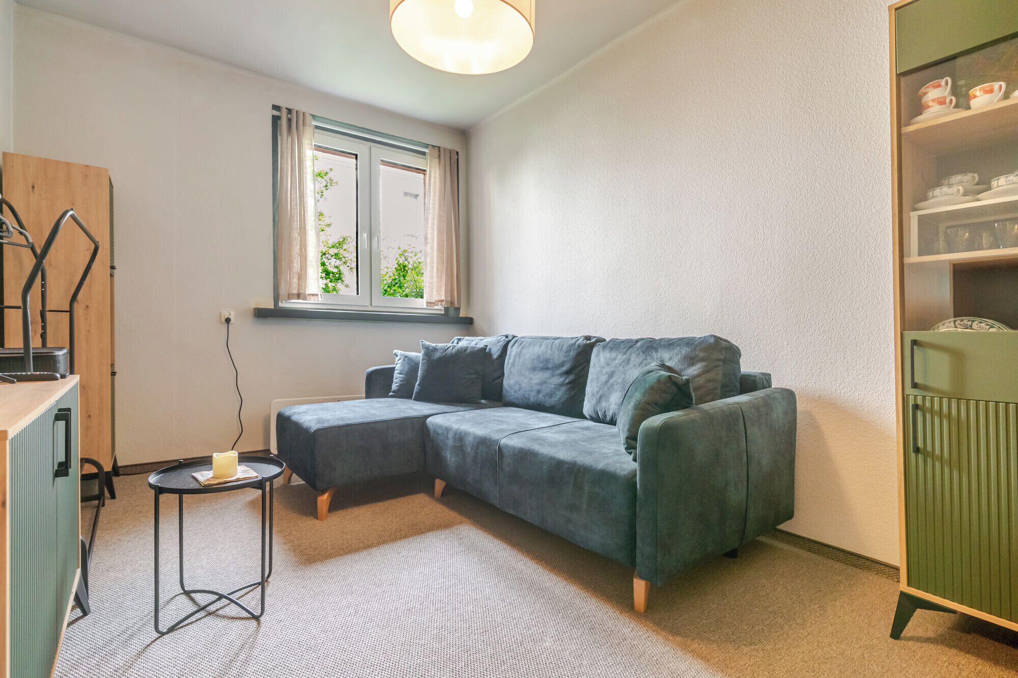 A modern living room with a sectional sofa, a small round table, and a window with curtains.