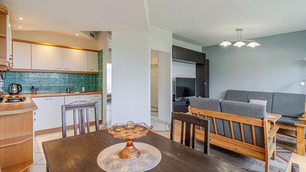 A modern kitchen with a dining area, a sofa, and a television. - Zawodzie Homely Apartment (Katowice)