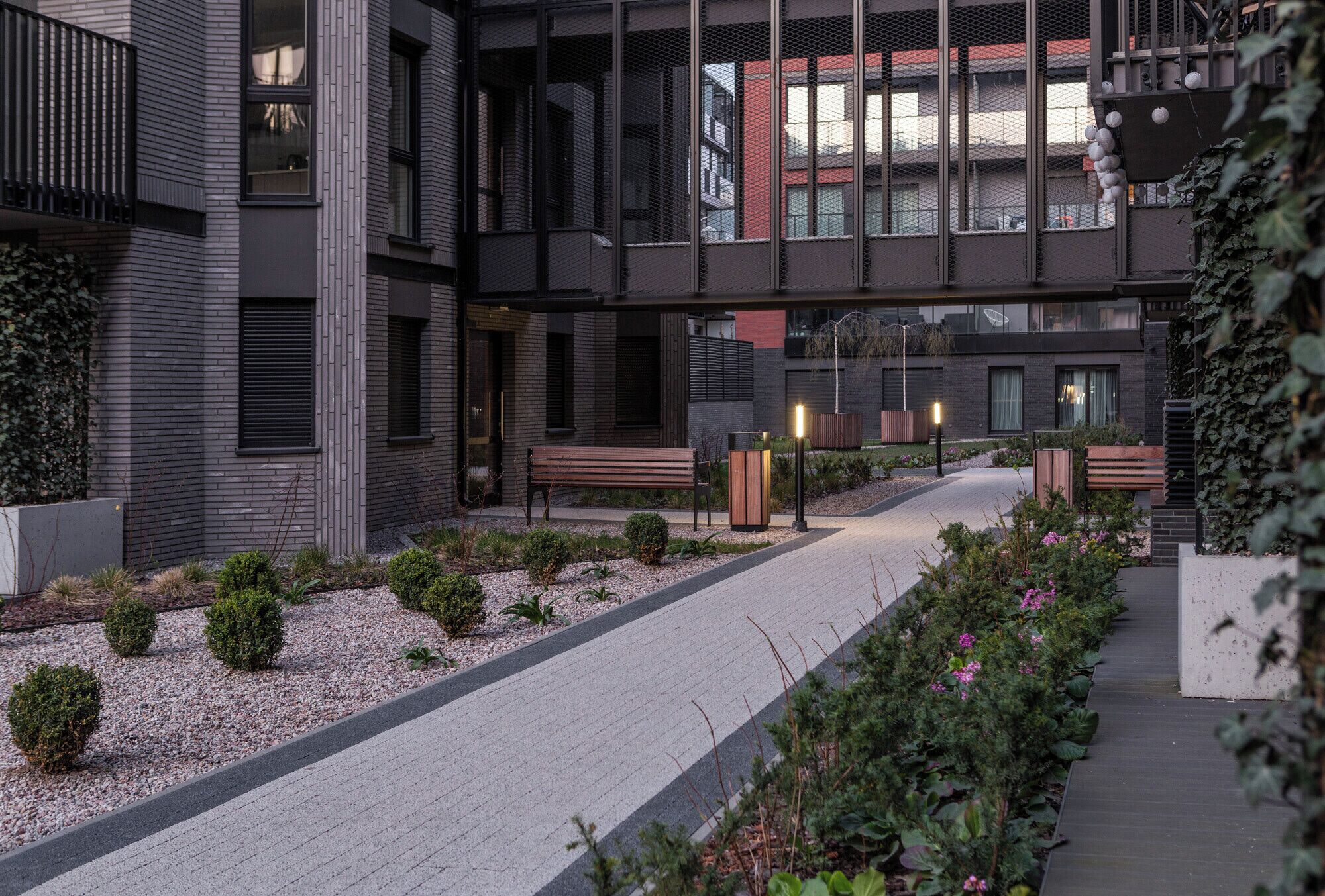 A modern building with a covered walkway, benches, and small plants.