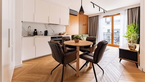 Eine moderne Küche mit weißen Schränken, einem runden Holztisch und braunen Stühlen.