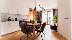 Eine moderne Küche mit weißen Schränken, einem runden Holztisch und braunen Stühlen.
