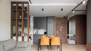 Un salon moderne comprenant un canapé, une table à manger, des chaises, une bibliothèque et un coin cuisine.
