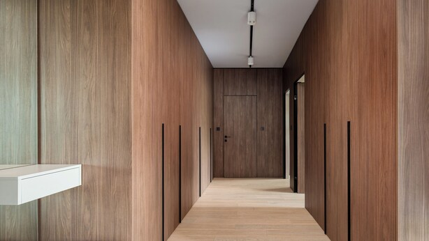 Un couloir avec des lambris en bois, un luminaire et un banc.