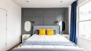 A bedroom with a bed, bedside tables, a mirror, and a window with curtains. - Spacious 3bd/3ba Rooftop w/Downtown Views* Garage! (Nashville)