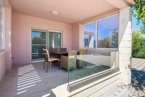 A balcony with a glass table, wicker chairs, and a sliding glass door. - Villa with swimming pool and hot tub (Metković)