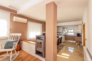 A modern living room with a fireplace, a dining area, and a kitchen.