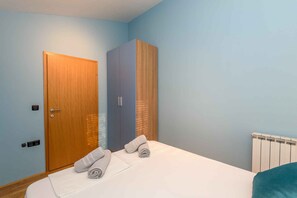 A bedroom with a bed, a wooden wardrobe, and a radiator.