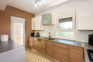A modern kitchen with a built-in microwave, a stainless steel sink, and wooden cabinetry.