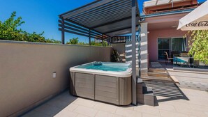 Ein Whirlpool mit Pergola, ein Poolbereich und ein Coca-Cola Sonnenschirm.