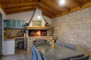 A rustic kitchen with a stone wall, wooden ceiling, and a dining area with a table and chairs. - Villa with swimming pool and hot tub (Metković)