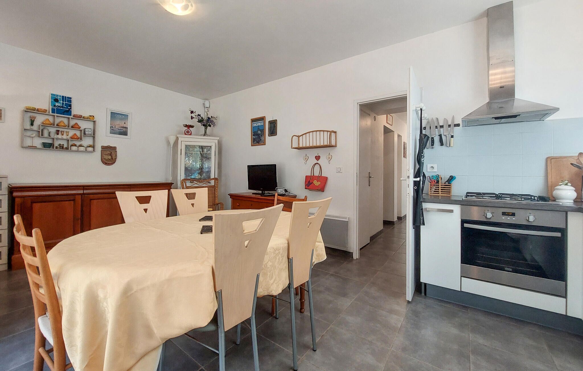 A dining area with a table and chairs, a kitchen with a stove and oven, and a hallway with a door leading to another room.