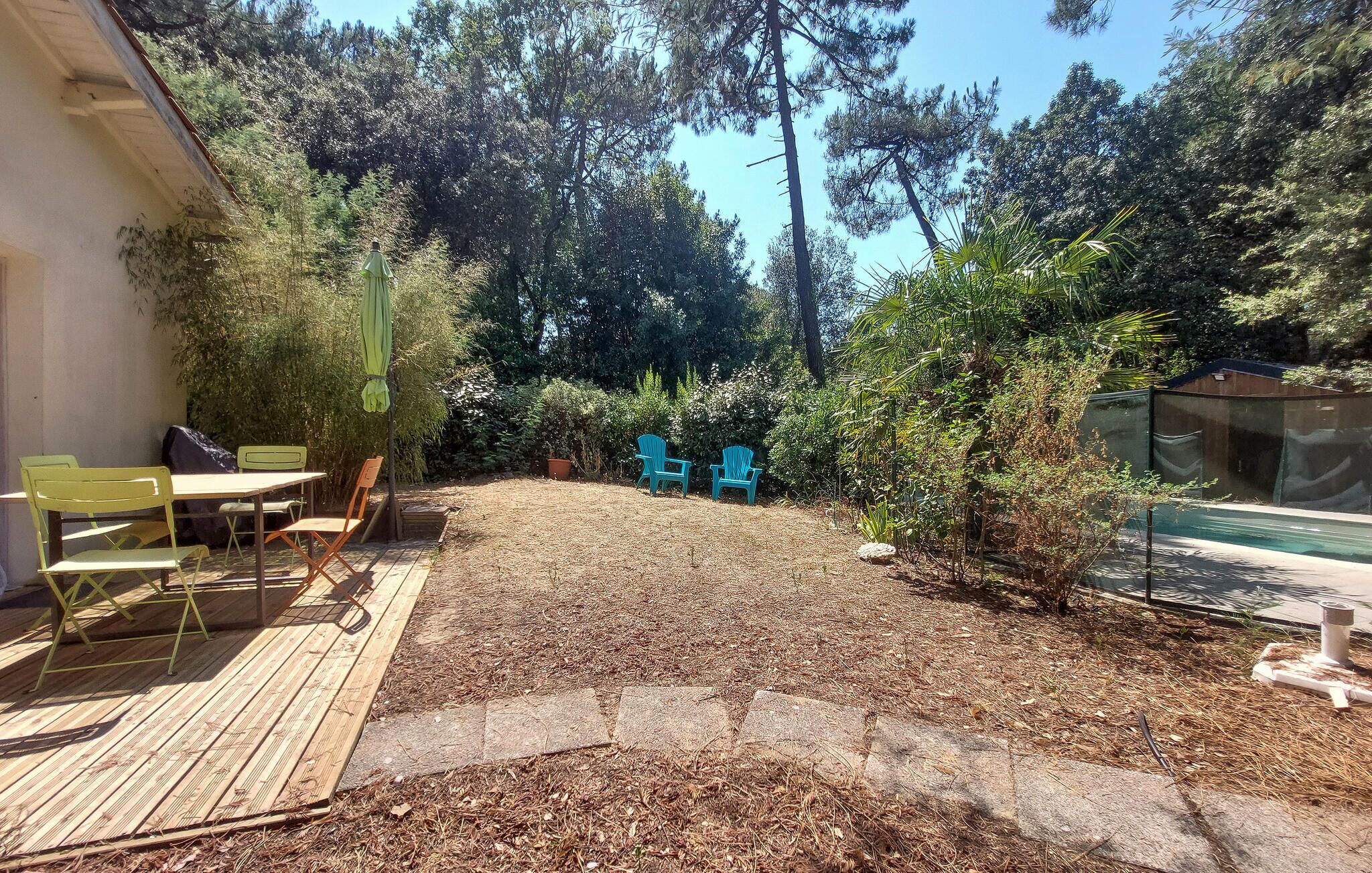 Een achtertuin met een houten terras, tuinmeubilair en een zwembad.