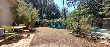A backyard with a wooden deck, outdoor furniture, and a swimming pool.