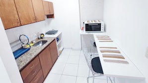 A compact kitchen with wooden cabinets, a microwave, a sink, and a small dining area.
