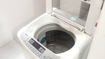 A front-loading washing machine with a control panel, a transparent door, and a small window above it.
