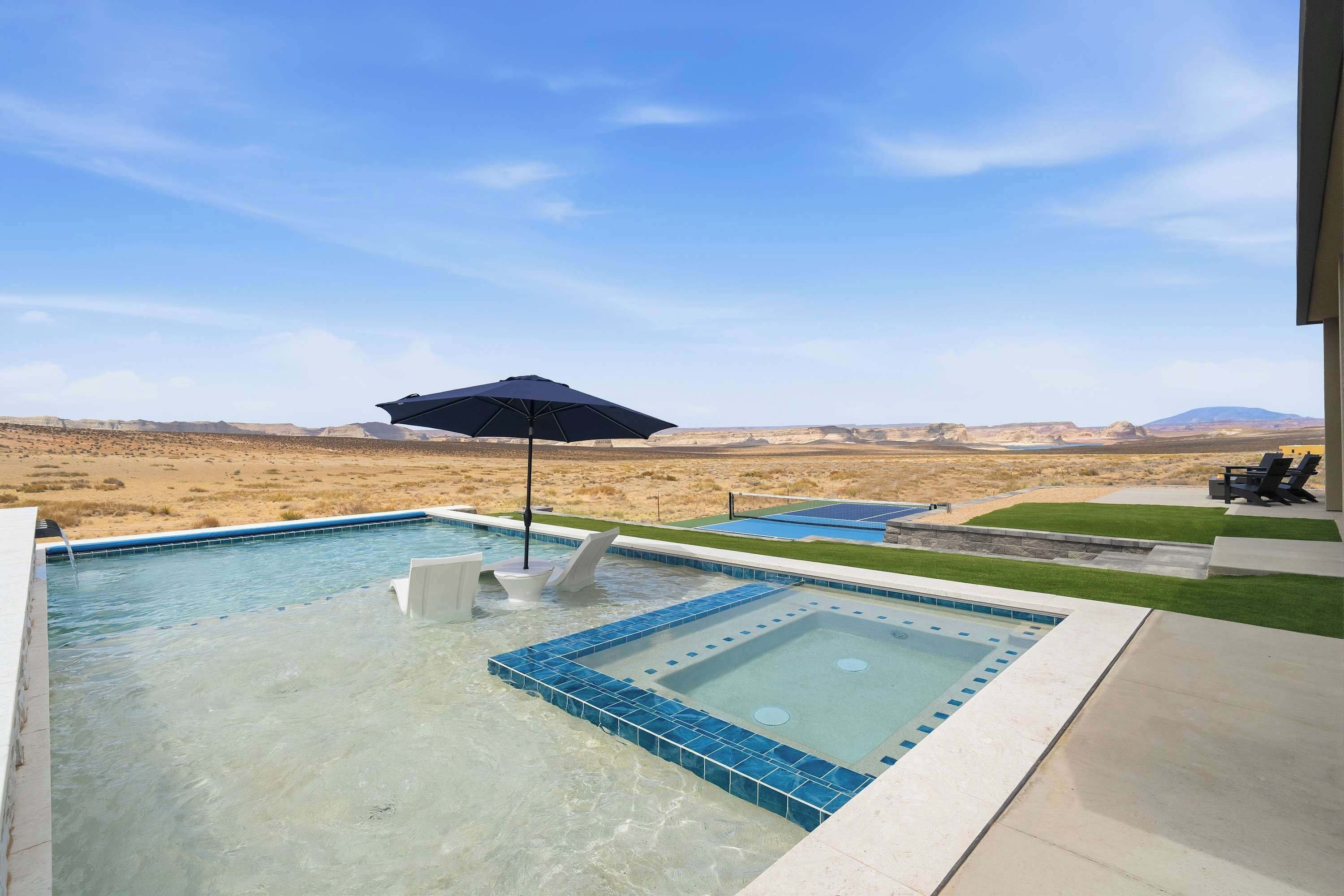 Une piscine avec un jacuzzi, une chaise longue et un parasol de patio.
