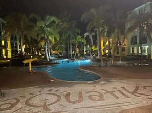 Ein Poolbereich mit Palmen und einem Gebäude im Hintergrund.