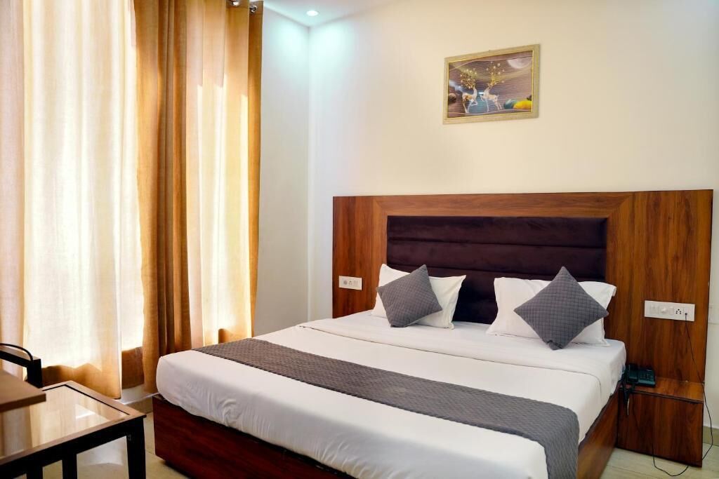Una habitación de hotel con cama, cortinas, un cuadro y una mesita de noche.