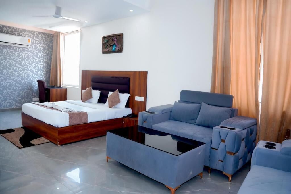 A modern hotel room with a bed, a sofa, a coffee table, and a ceiling fan.