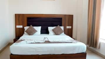 Una cama bien hecha con cabecera de madera, ropa de cama blanca y dos almohadones decorativos.