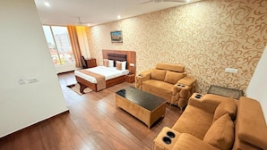 A hotel room with a bed, a sofa, a coffee table, and a patterned wall.