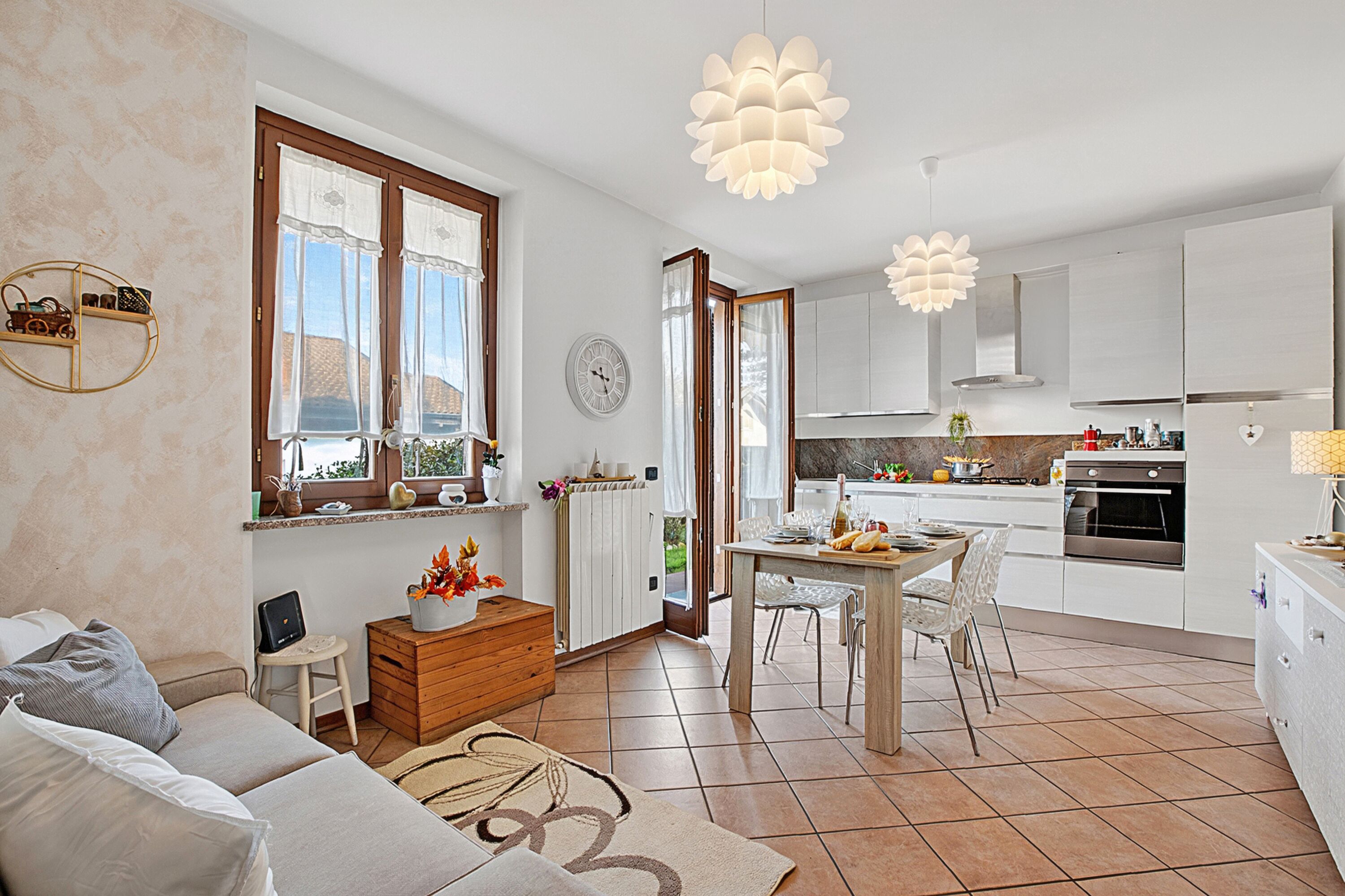 A modern kitchen with white cabinets, a dining area with a table and chairs, and a living room with a sofa and a coffee table.