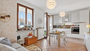 Een moderne keuken met witte kastjes, een eethoek met een tafel en stoelen, en een woonkamer met een bank en salontafel.