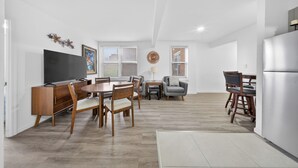 Een moderne keuken met een eethoek, houten meubels en een grote flatscreen televisie.