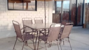 Un patio con una mesa y sillas, una maceta colgante y un muro de ladrillo.