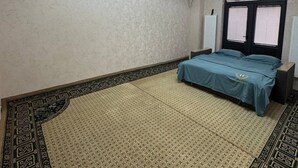 Un dormitorio con cama, ventilador de techo, equipo de aire acondicionado y ventana con persianas.