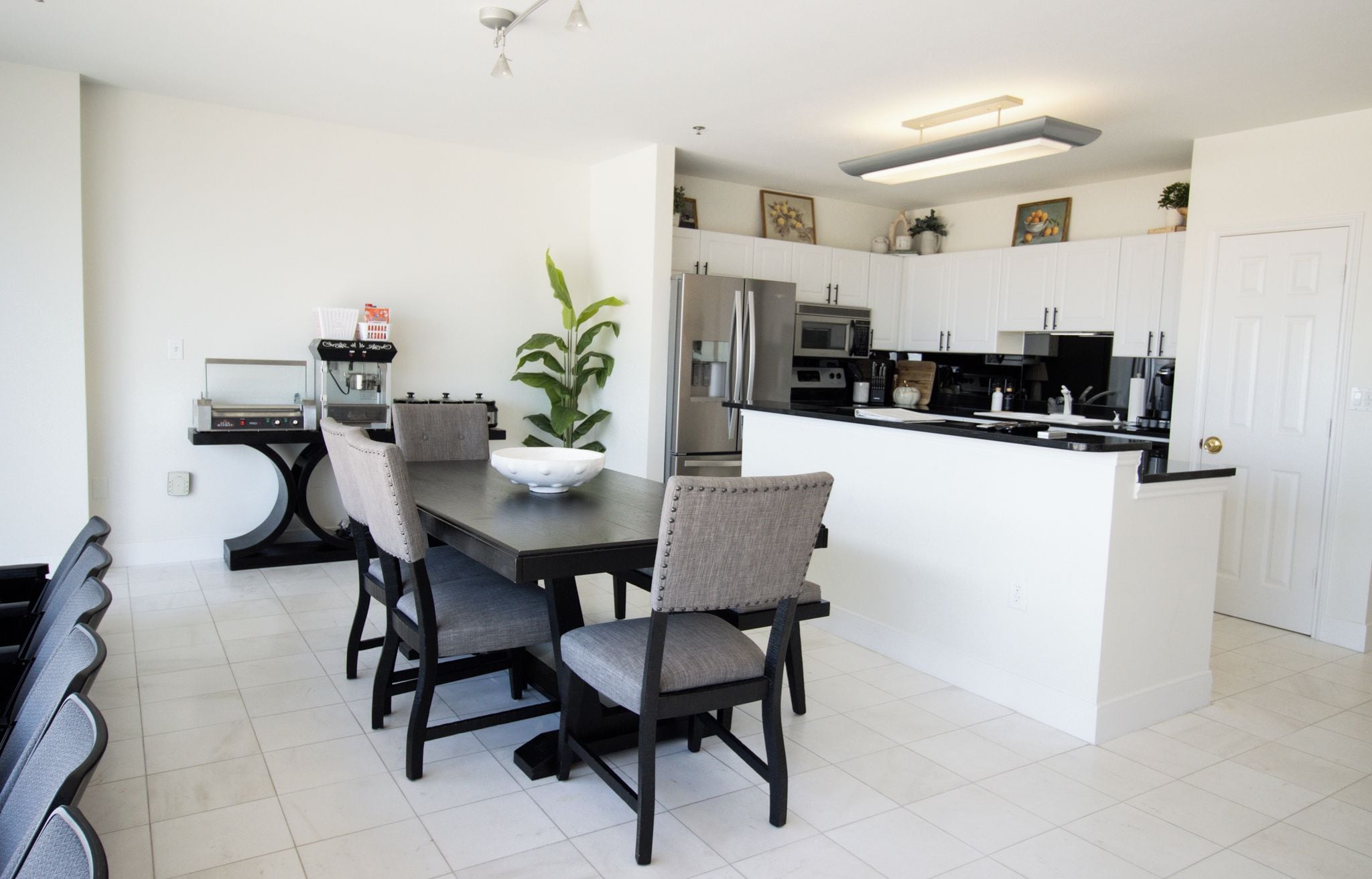 A modern kitchen with white cabinets, a stainless steel refrigerator, and a black countertop.