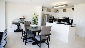 A modern kitchen with white cabinets, a stainless steel refrigerator, and a black countertop.