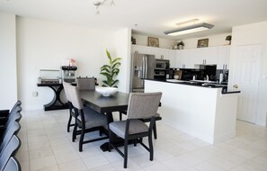 A modern kitchen with white cabinets, a stainless steel refrigerator, and a black countertop.