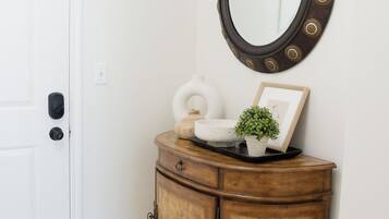 A white door, a wooden cabinet with a mirror, and a small plant on the cabinet.