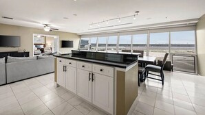 Una cucina moderna con un'isola grande, un'area pranzo con vista e un soggiorno con divano e televisione.