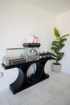 A kitchen with a coffee machine, a potted plant, and a tiled floor.