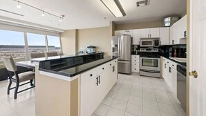 Una cucina moderna con isola centrale, elettrodomestici in acciaio inossidabile e un'ampia finestra con vista sulla città.