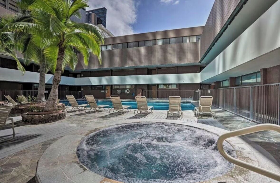 A hotel courtyard with a hot tub, lounge chairs, and a palm tree.
