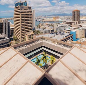 A high-rise building with a rooftop pool surrounded by other buildings and a port in the background. - Chic studio condo with Free Parking & AC in vibrant Downtown Honolulu (Honolulu)